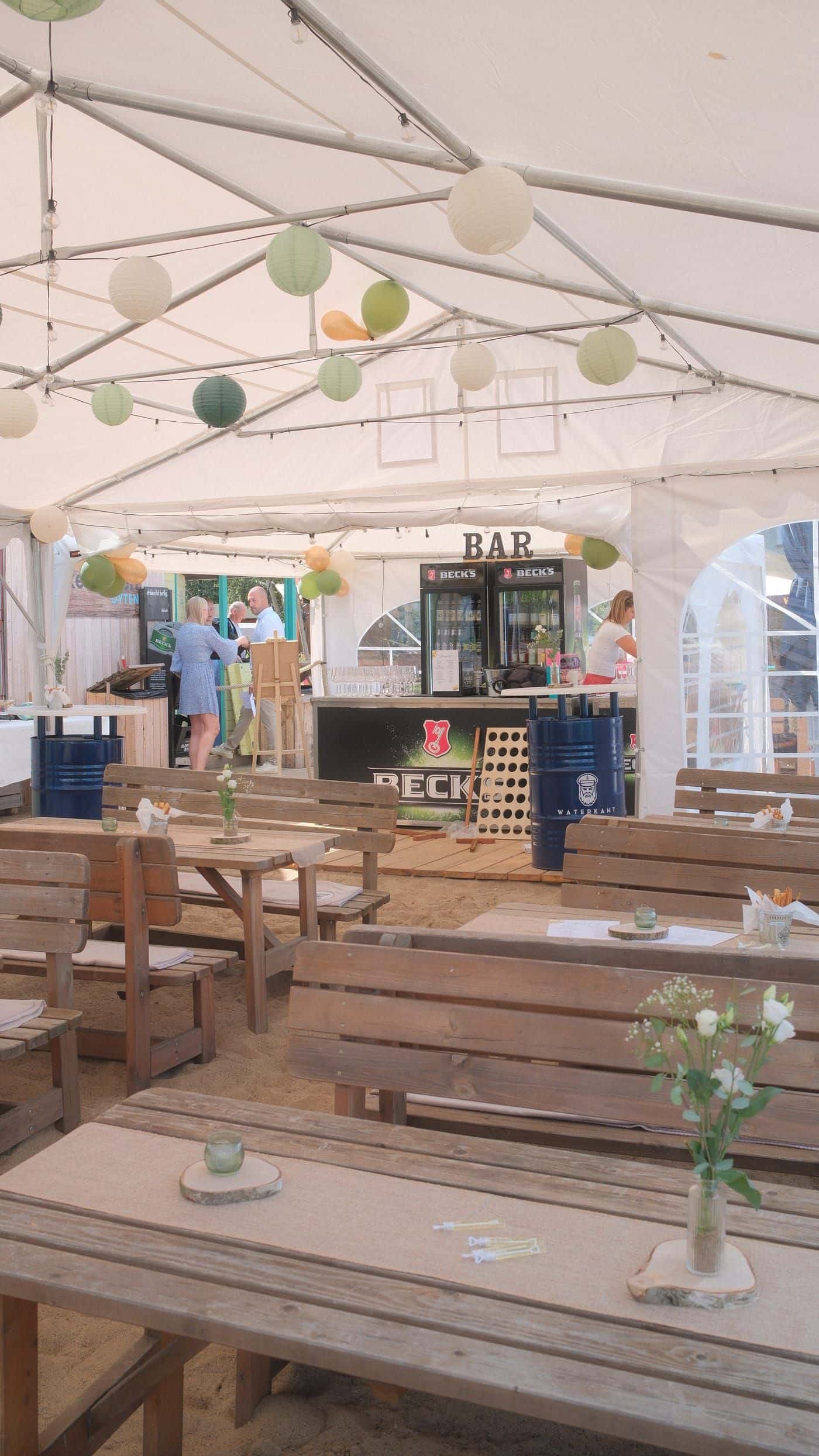 Weißes Festzelt mit Bar, Beck’s-Kühlschränken und Holzbänken, Lampions unter der Decke